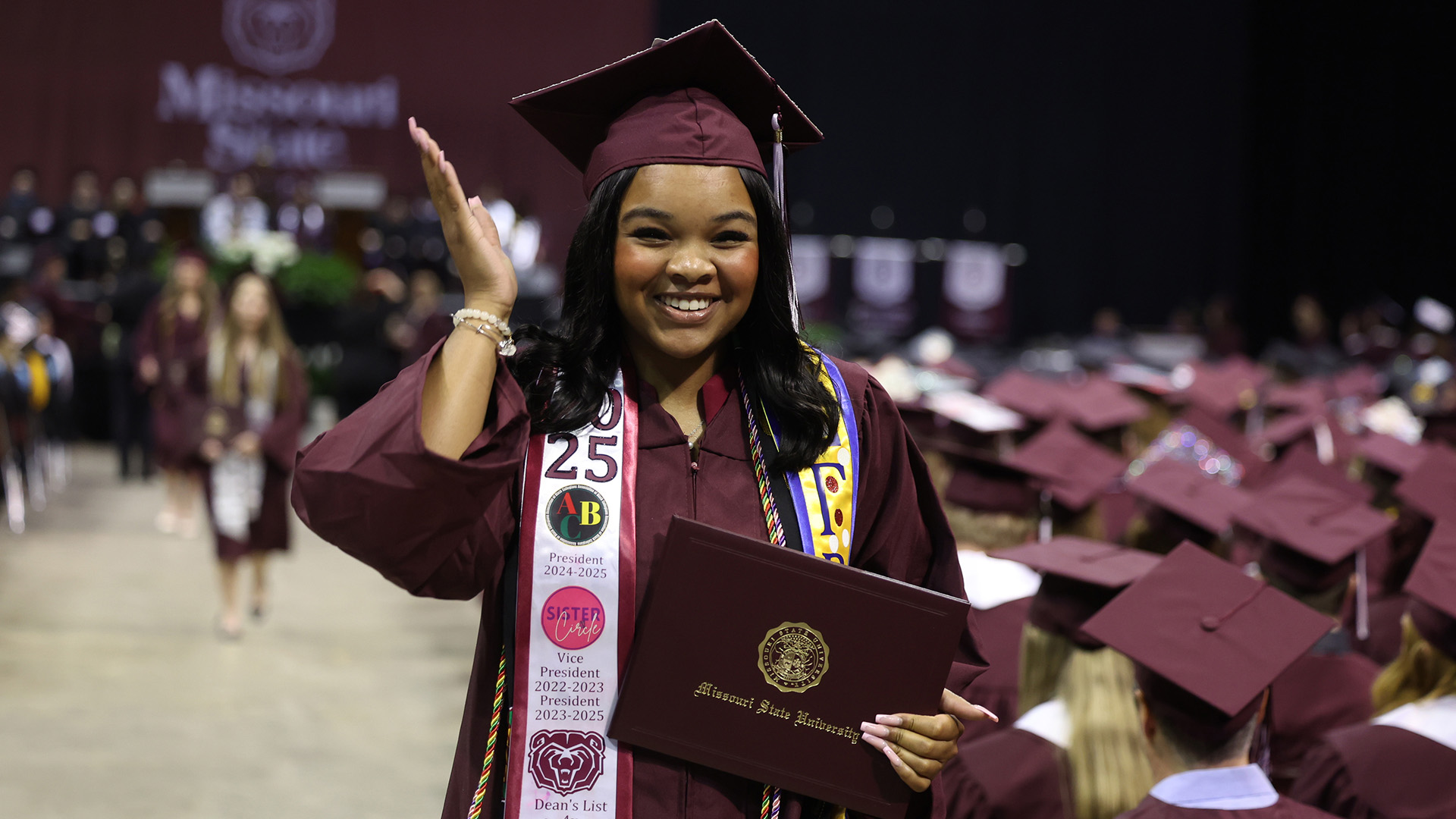 Woman holding her degree and smiling after graduation