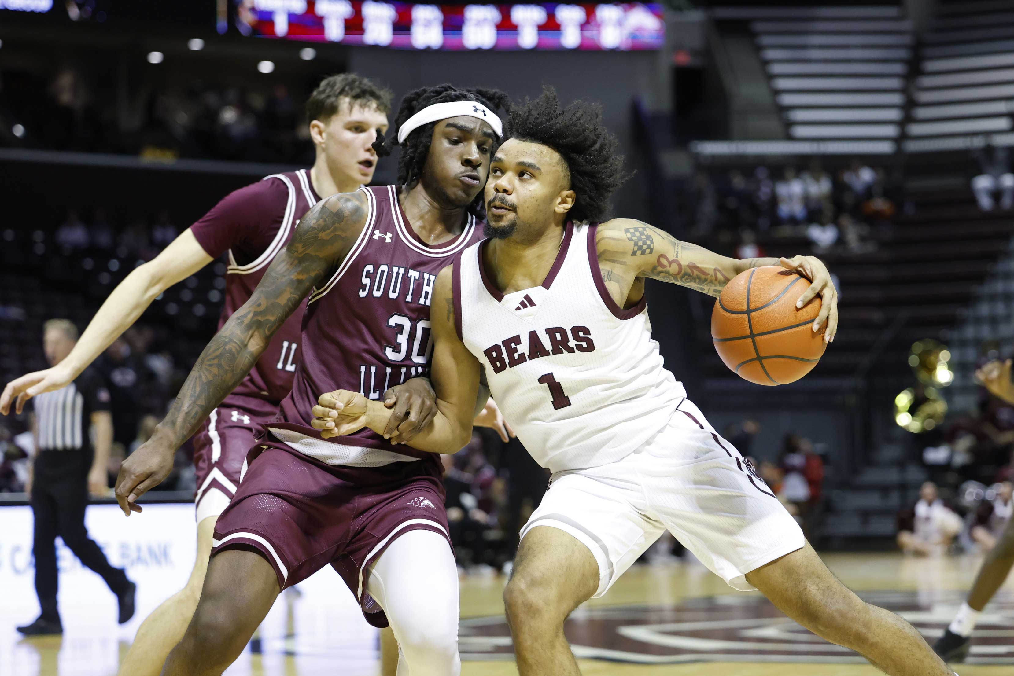 Bears basketball player drives toward the basket, pushing a defender